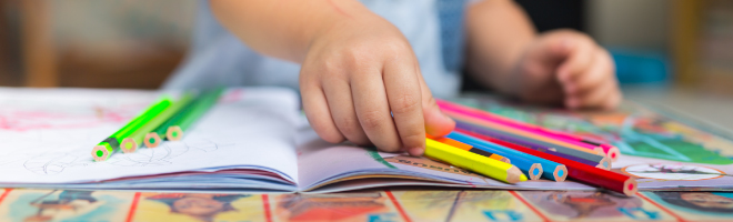 manos de un niño coloreando un libro, regreso a clases.