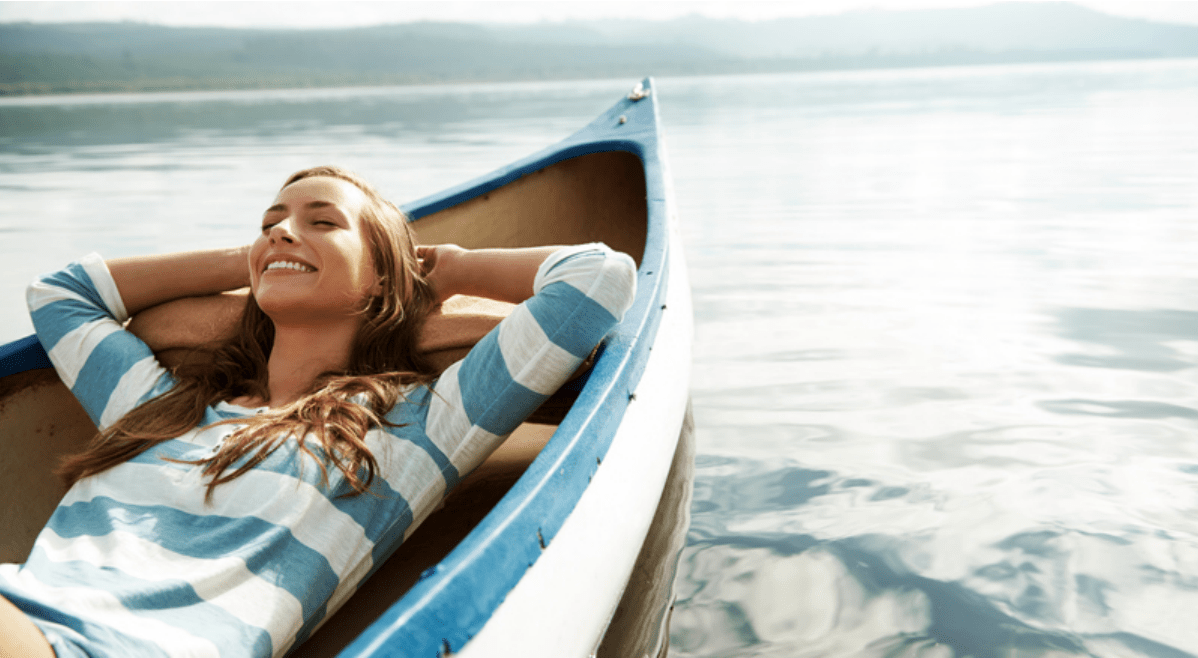 Mujer acostada relajada y feliz flotando en un bote 