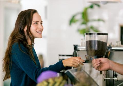 Mujer pagando con su tarjeta de crédito en una cafetería