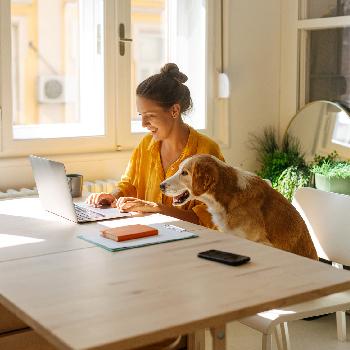 Mujer con su mascota trabajando en su vivienda adquirida a través de Viviendas adjudicadas de BAC como parte del Credito Hipotecario