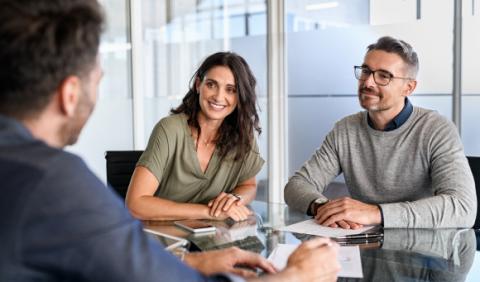 Personas sonrientes recibiendo una explicación sobre la importancia de invertir con BAC