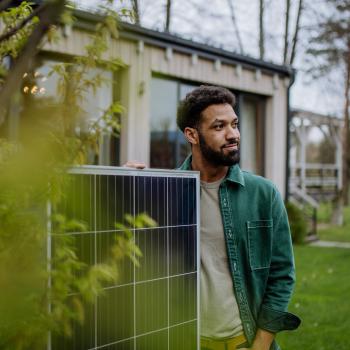 persona sosteniendo un panel solar de su vivienda sostenible conseguida a través del credito hipotecario para vivienda sostenible de BAC