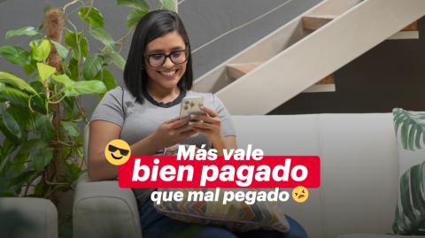 Mujer sonriente en su telefono pagando el marchamo en Banca Movil de BAC