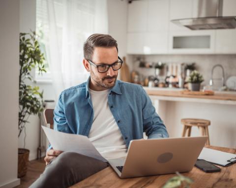 Person concentrada en su computadora verificando los beneficios en su cuenta gracias al deposito a plazo digital de BAC El Salvador