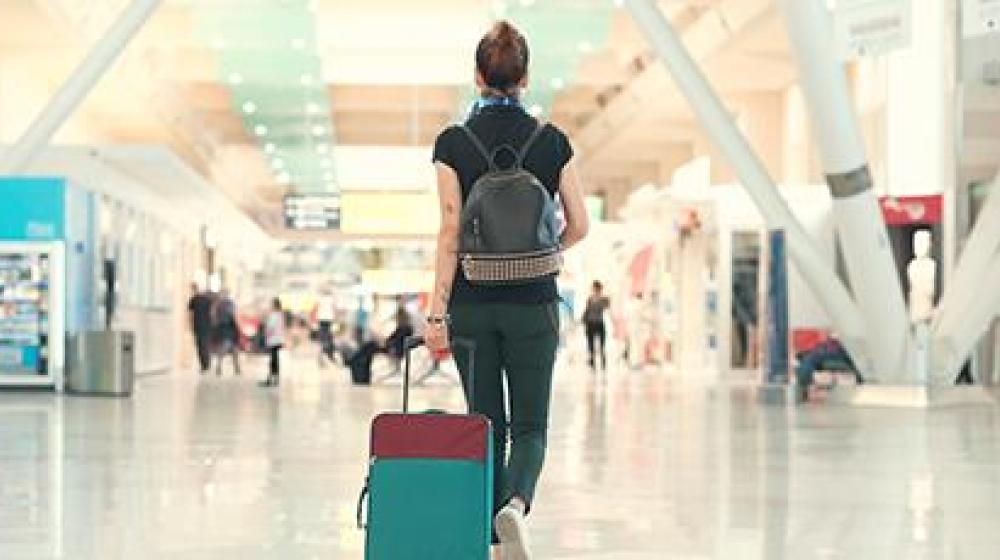 Persona caminando en aeropuerto mientras lleva su maleta