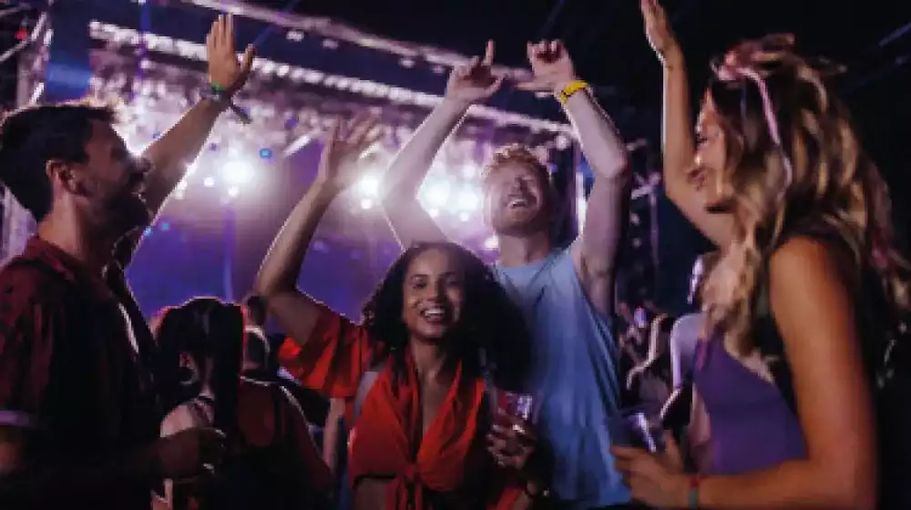 Una joven multitud de amigos multiétnicos está bailando en un concierto