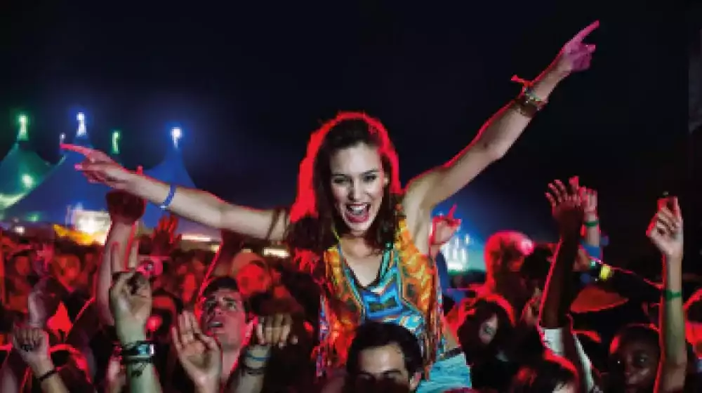 Animando a las mujeres sobre los hombros de los hombres en el festival de música