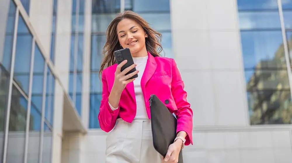 Mujer feliz revisando sus correos electronicos al mismo tiempo que BAC El Salvador hace crecer sus ahorros con un Deposito a Plazo Digital