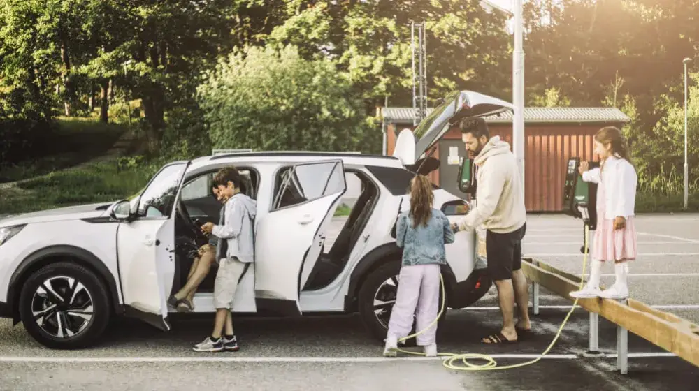 Familia con su vehiculo electrico realizando una parada para cargar el vehiculo