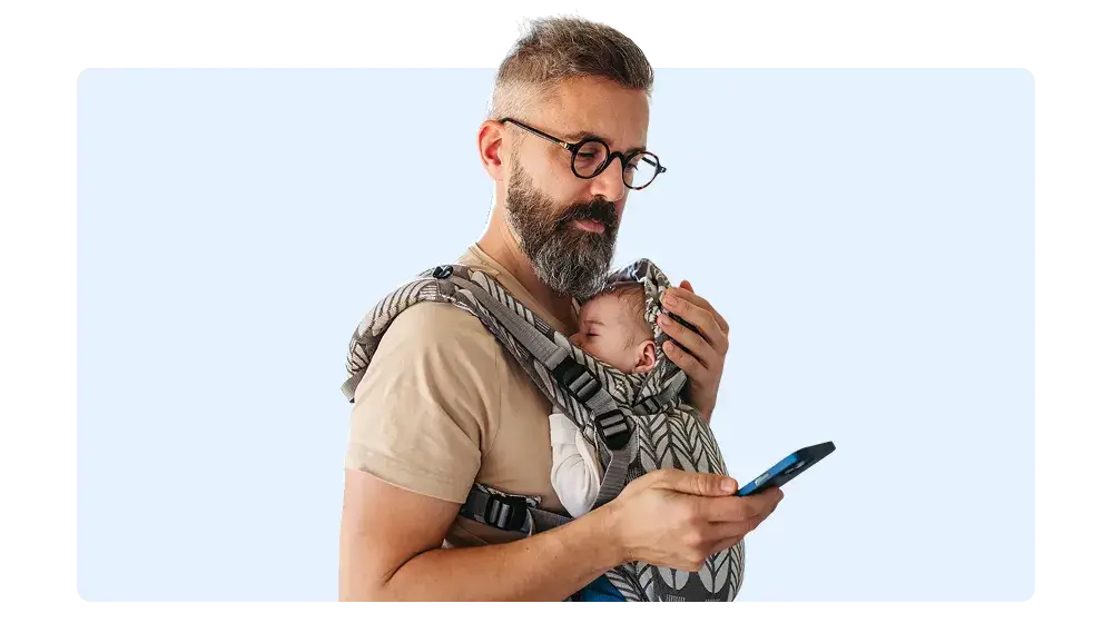 Imagen de padre de familia con su hijo en brazos mientras revisa su cuenta preferente de BAC