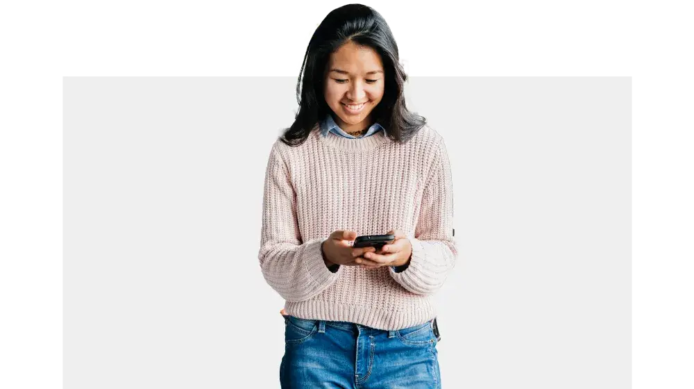 Mujer sonriente viendo la pantalla de su celular, mientras crea su cuenta planilla con BAC Honduras