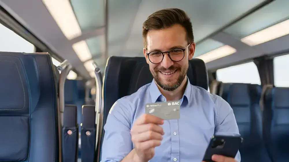 Persona sentada en un asiento de avion con su tarjeta Millas de BAC Guatemala
