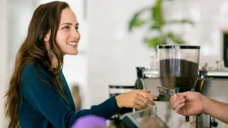 Mujer pagando con su tarjeta de crédito en una cafetería