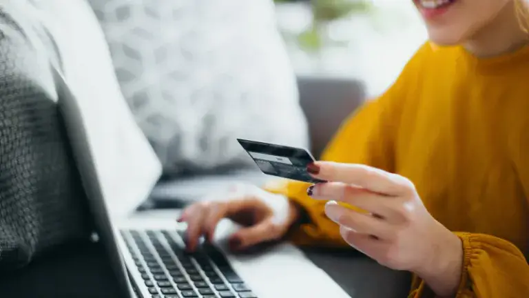 Dama con laptop y su tarjeta en la mano