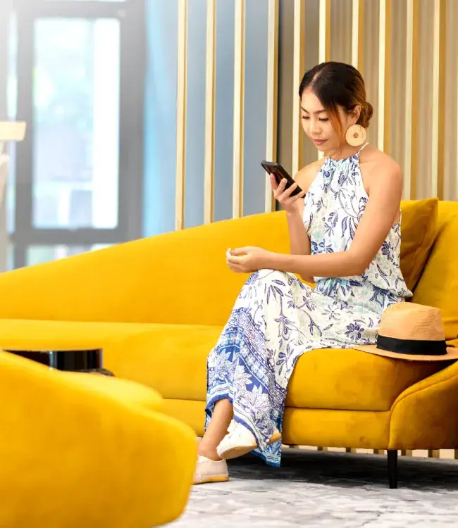 Mujer feliz viendo su celular en sala vip de aeropuerto
