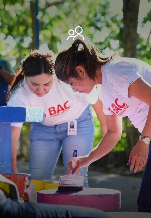 Mujeres colaboradoras de BAC Credomatic pintan bancas de parque en actividad social